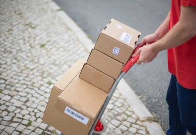 Courier wheeling a stack of parcels
